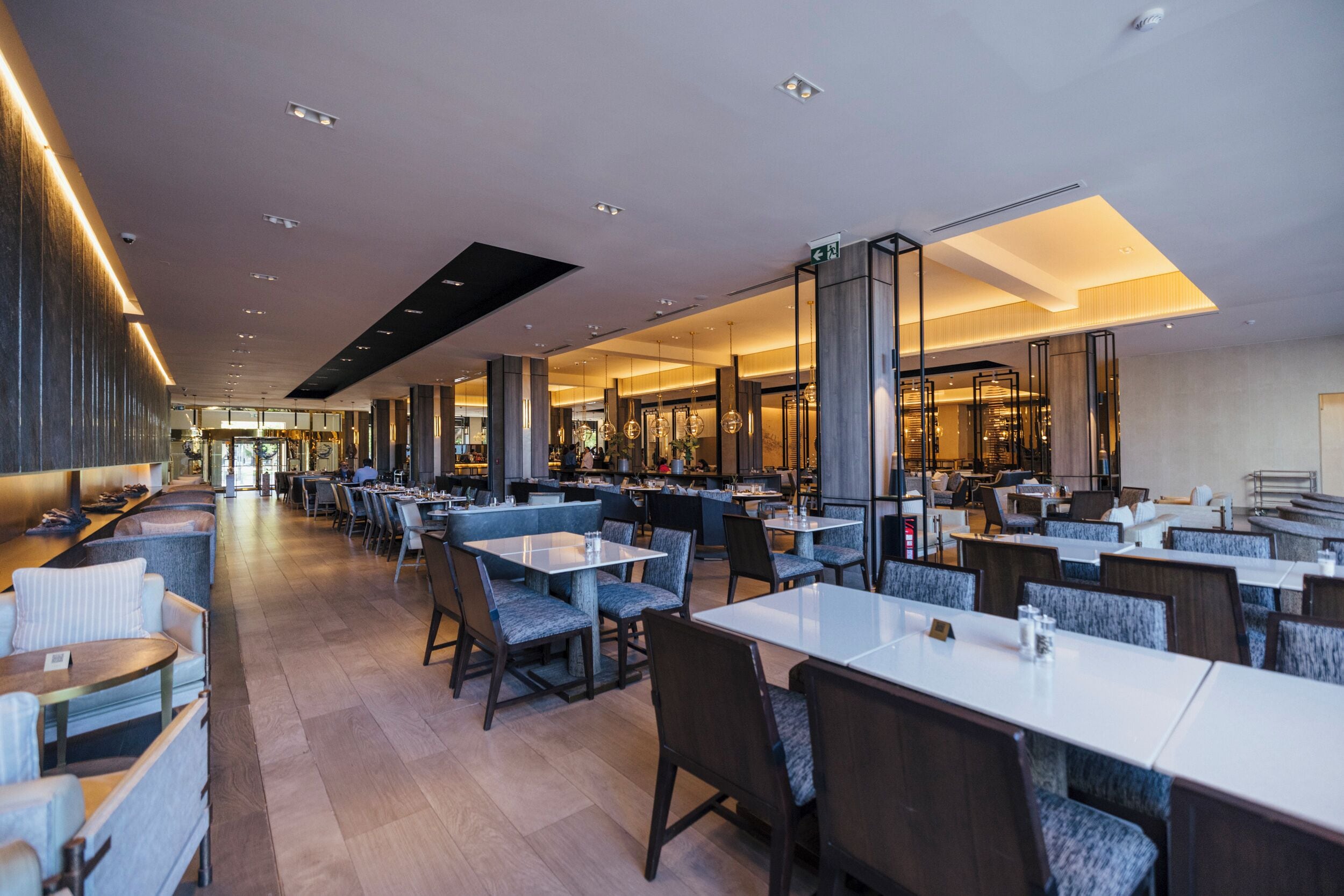 A spacious restaurant with multiple dining areas, high ceilings, and modern lighting.