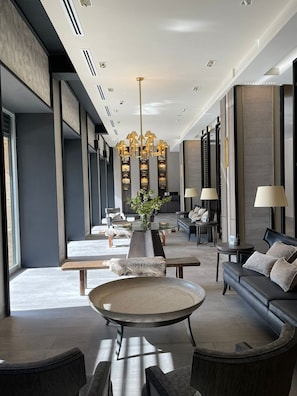 Un hall d’hôtel moderne avec une table ronde centrale, des canapés et un lustre.