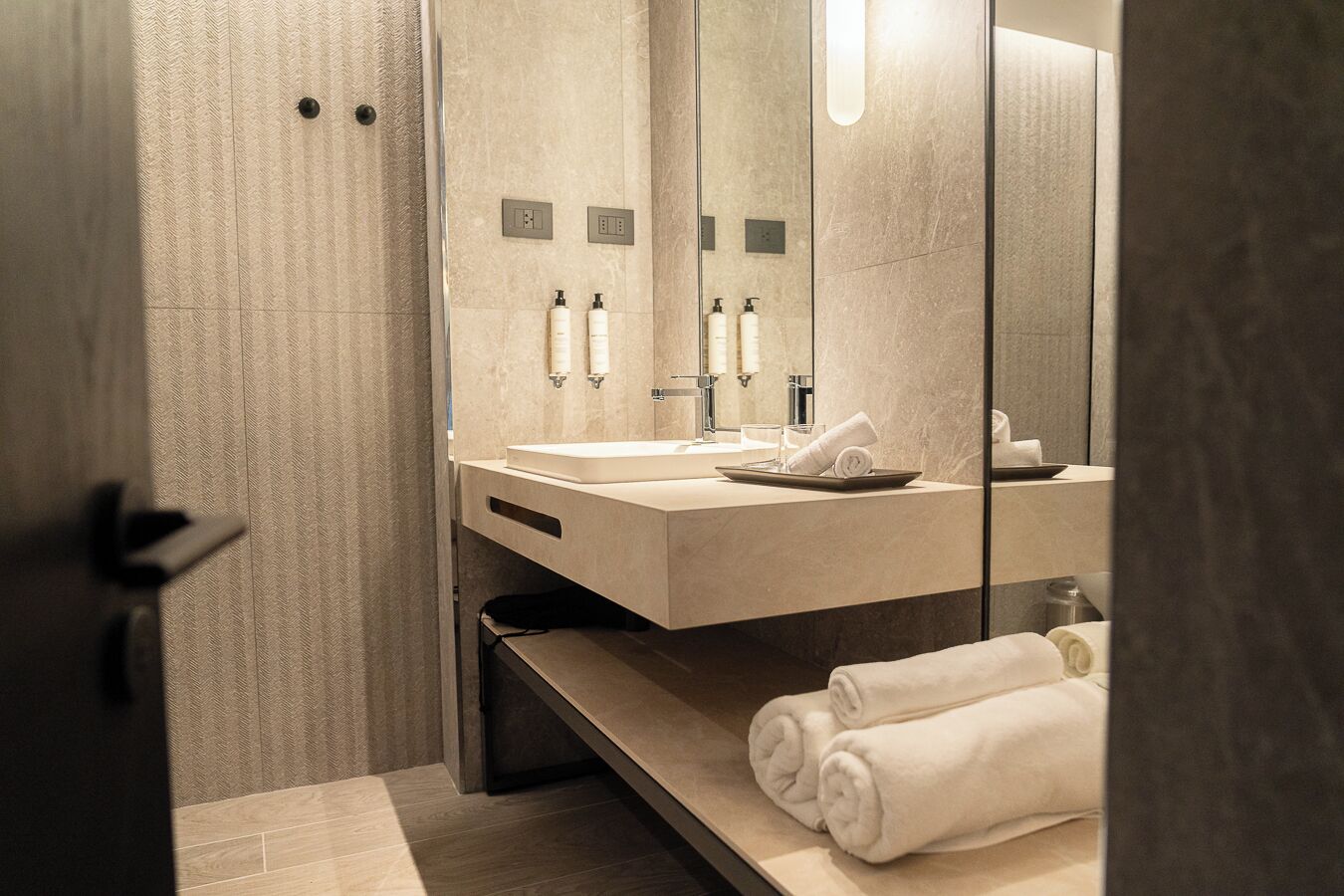 A modern bathroom with a large mirror, a sink, and a towel rack.