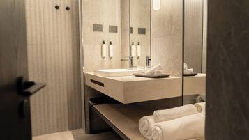 A modern bathroom with a large mirror, a sink, and a towel rack.