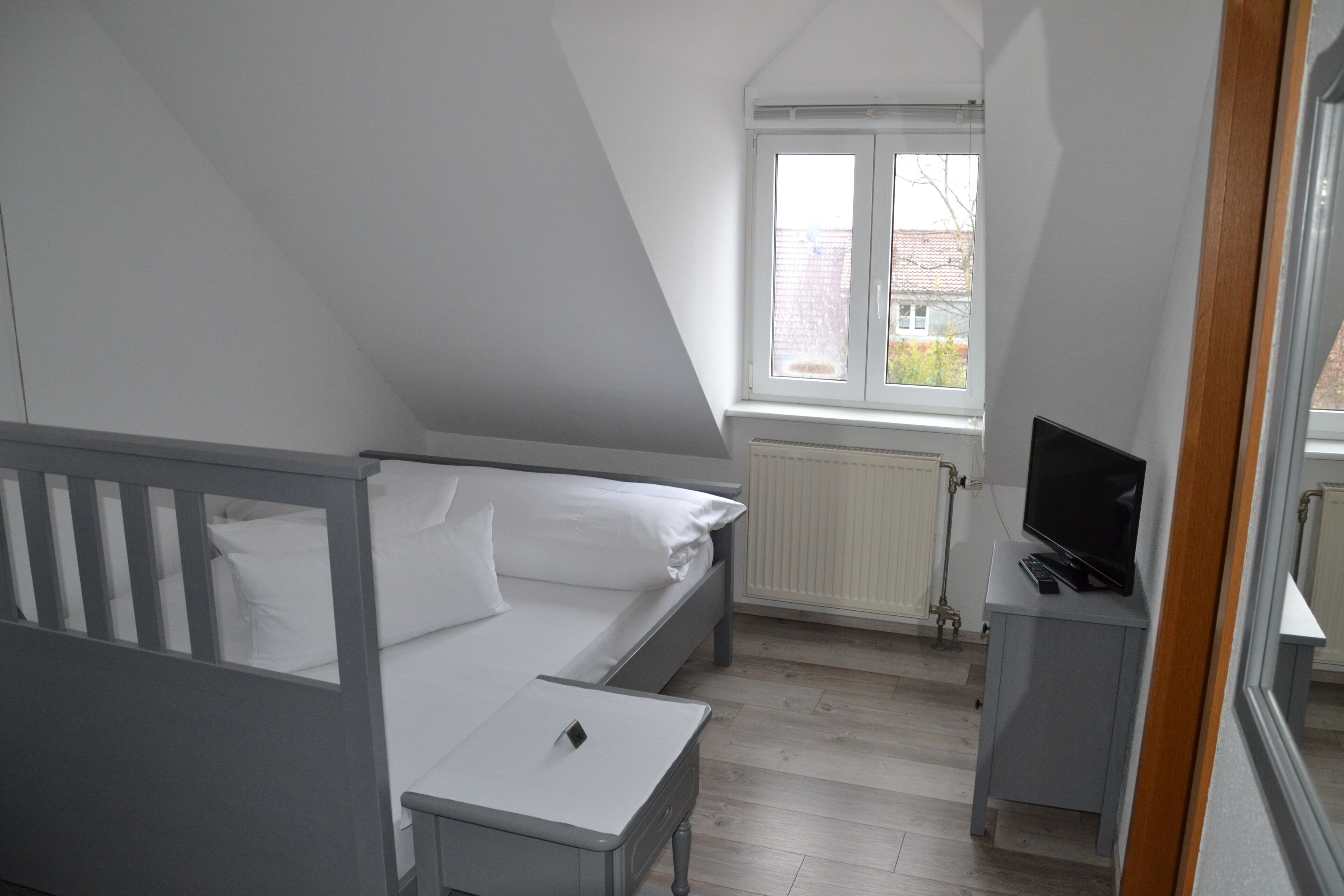 Un dormitorio con una cama, un escritorio con computadora y una ventana.