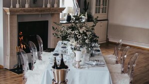 A formal dining setup with a white tablecloth, clear chairs, and a centerpiece with flowers and candles. - Hotel Zur Tanne (Fischingen)