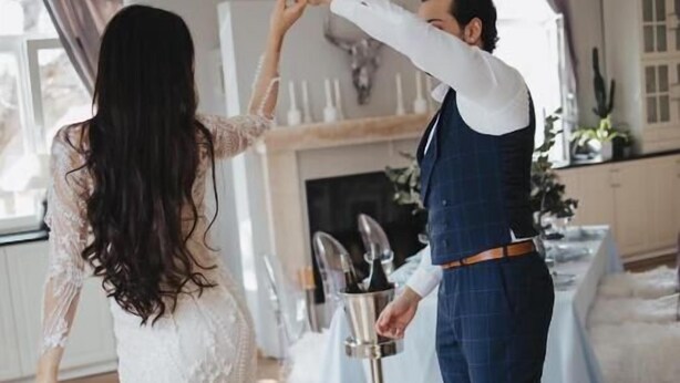 A couple dancing in a room with a fireplace, a table with a white tablecloth, and a chandelier. - Hotel Zur Tanne (Fischingen)