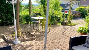 An outdoor patio with wicker furniture, a table with a vase, and a pergola. - Hotel Zur Tanne (Fischingen)