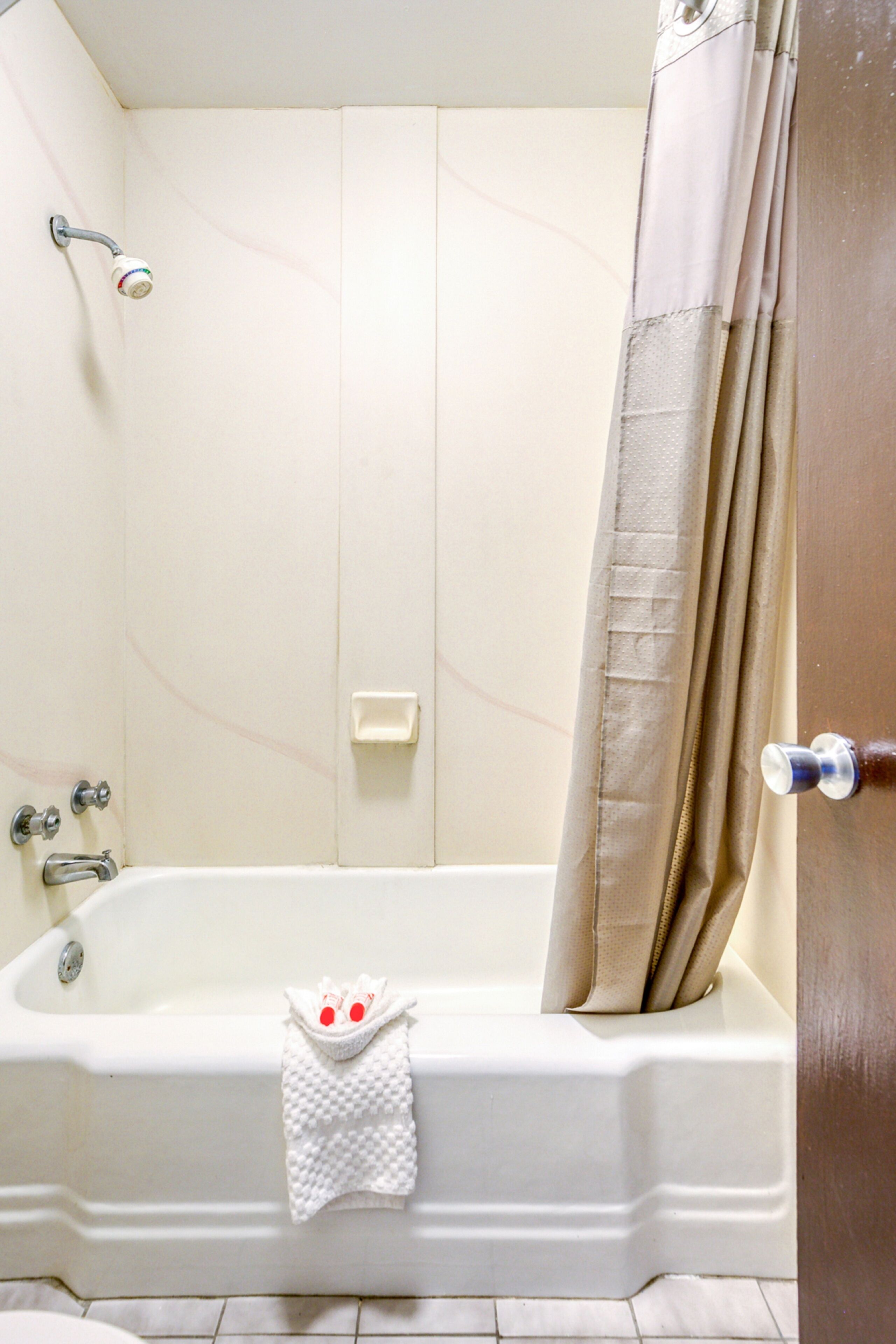 A bathroom with a bathtub, shower, and a towel rack with a towel.