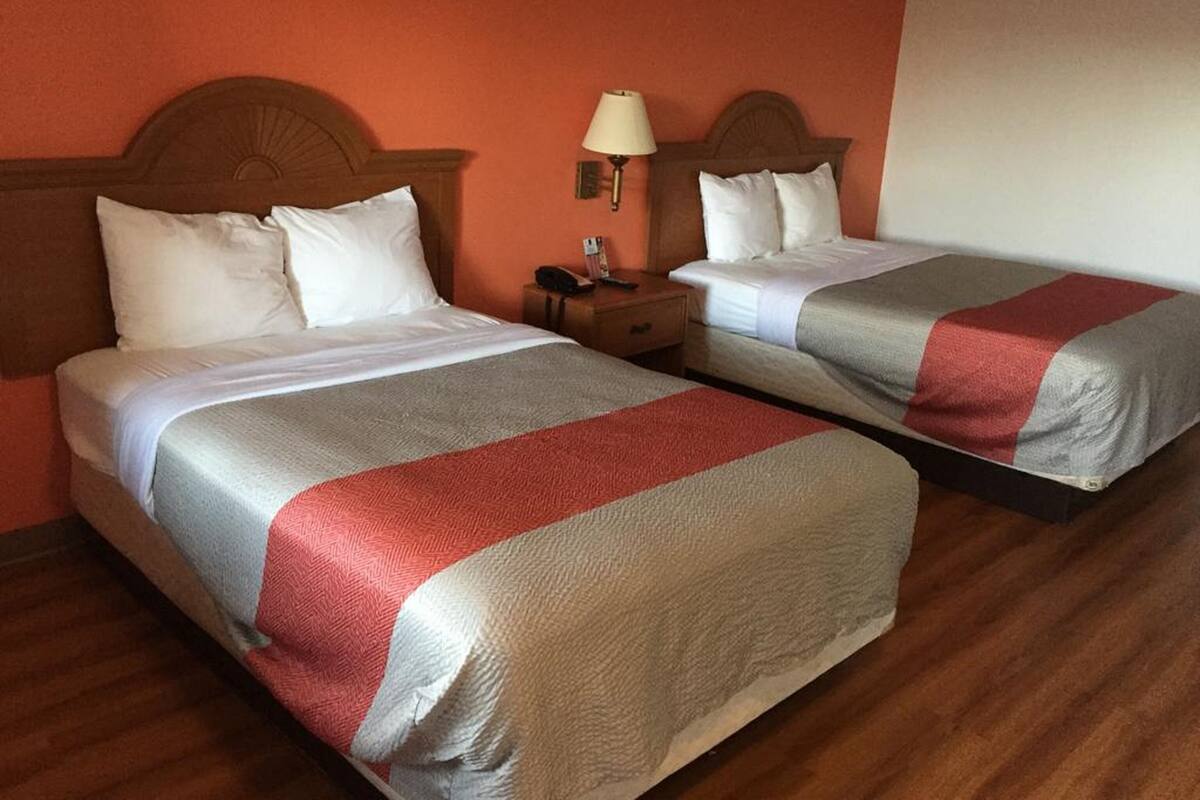 Two twin beds with matching headboards and footboards, a nightstand with a lamp, and a wooden floor.