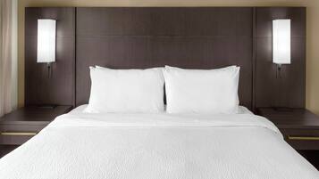 A hotel room with a large bed, two bedside tables, and wall-mounted lamps.