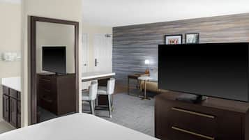 Une chambre d’hôtel comprenant un lit, un bureau, une chaise, une télévision, une armoire et une salle de bain.