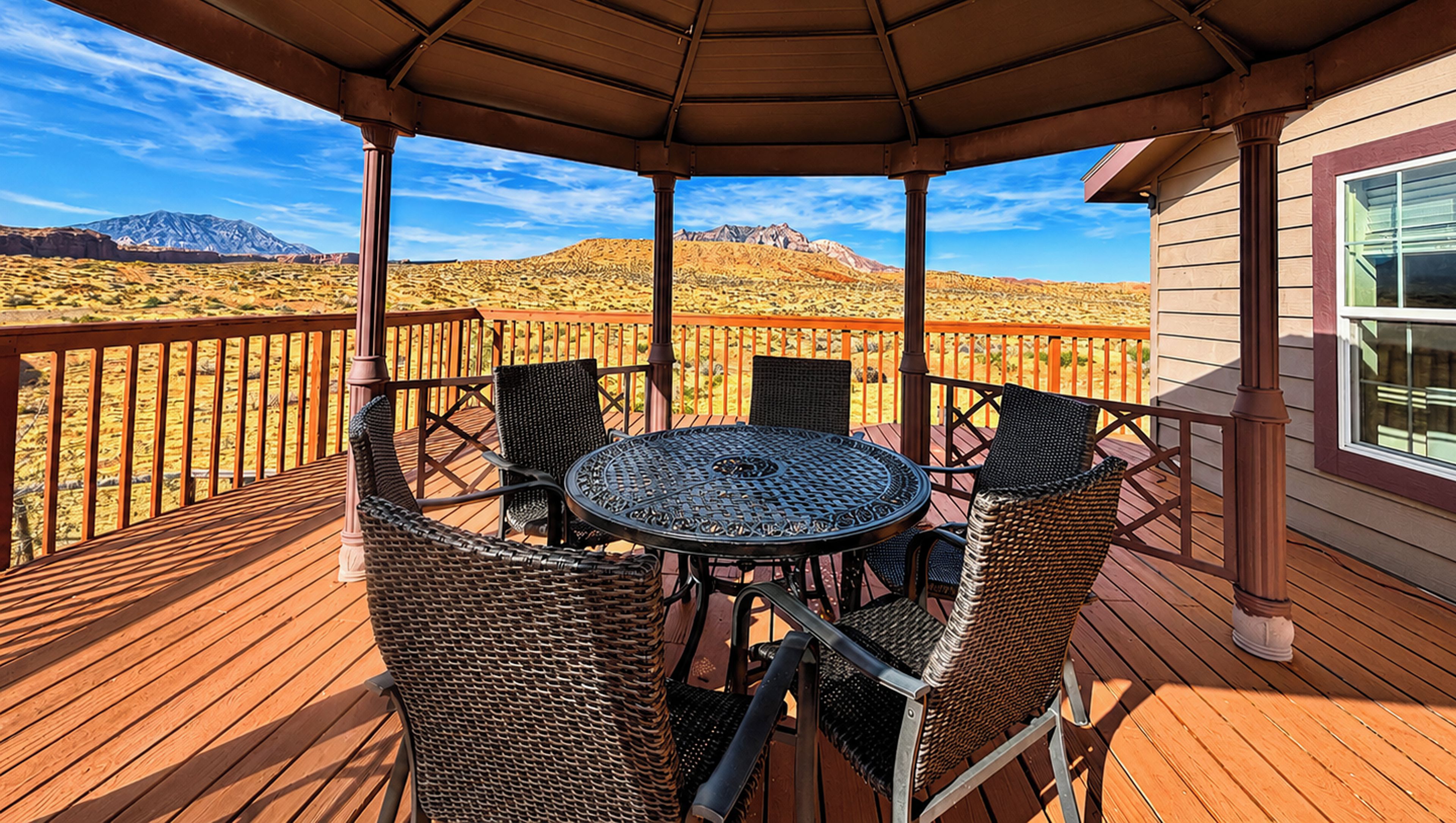 Un espacio de estar al aire libre cubierto con una mesa y sillas, con vistas a un paisaje desértico y montañas.
