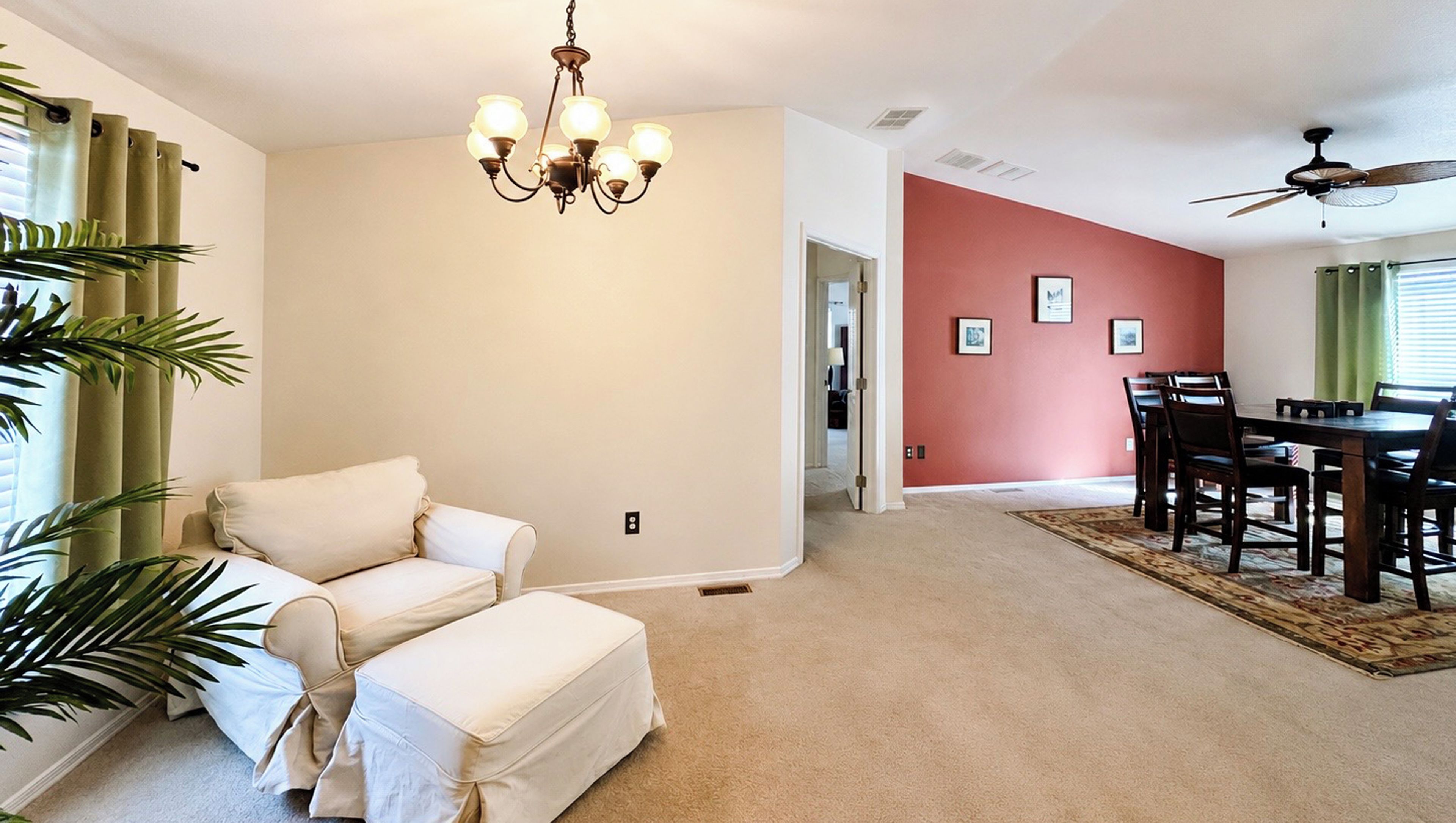 A living room with a beige sofa, a dining area with a table and chairs, and a ceiling fan.