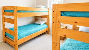 Un lit superposé avec un lit en bas et un lit simple en haut, tous deux dotés de draps bleus.