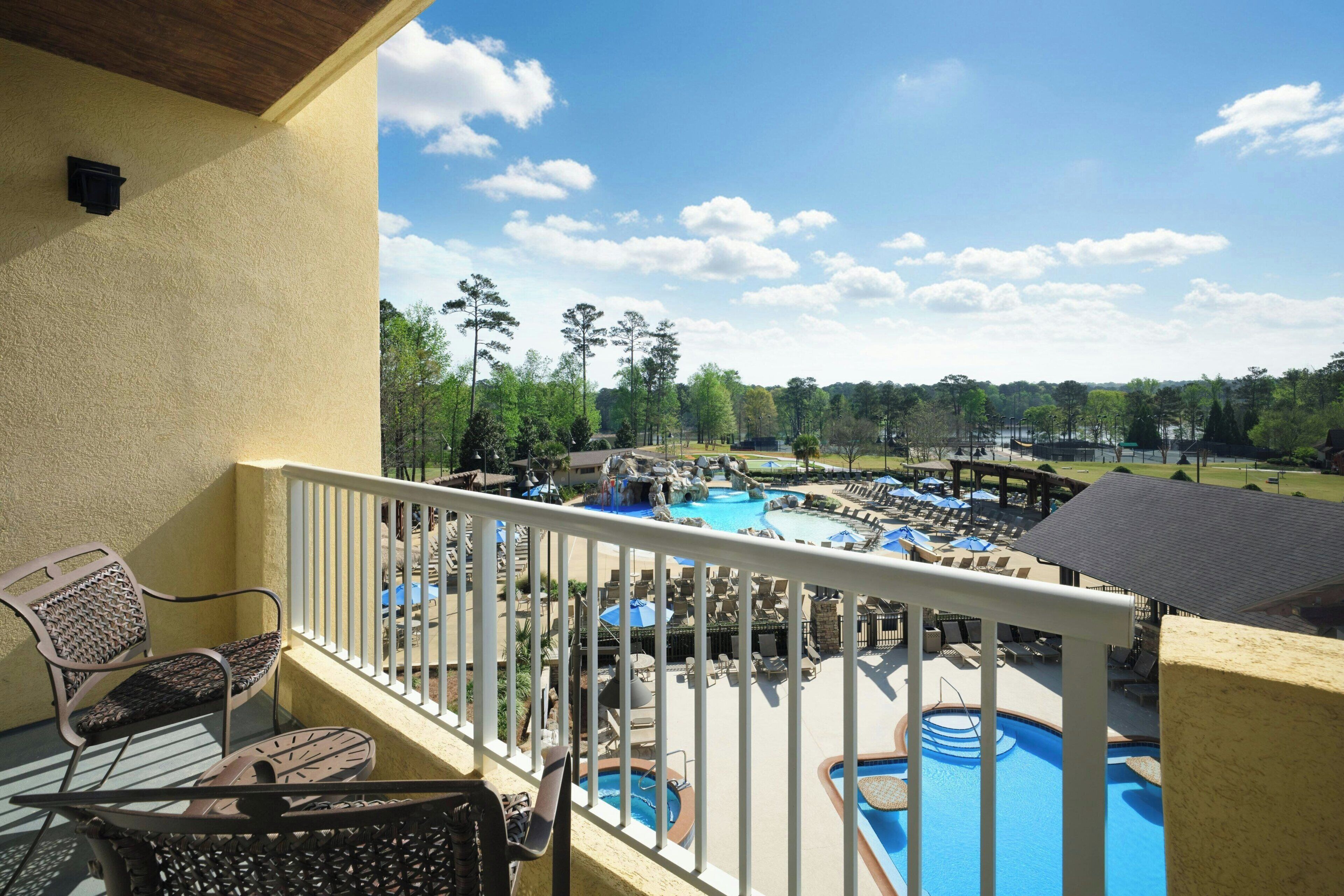 A balcony with a view of a pool area, including lounge chairs and a water slide.