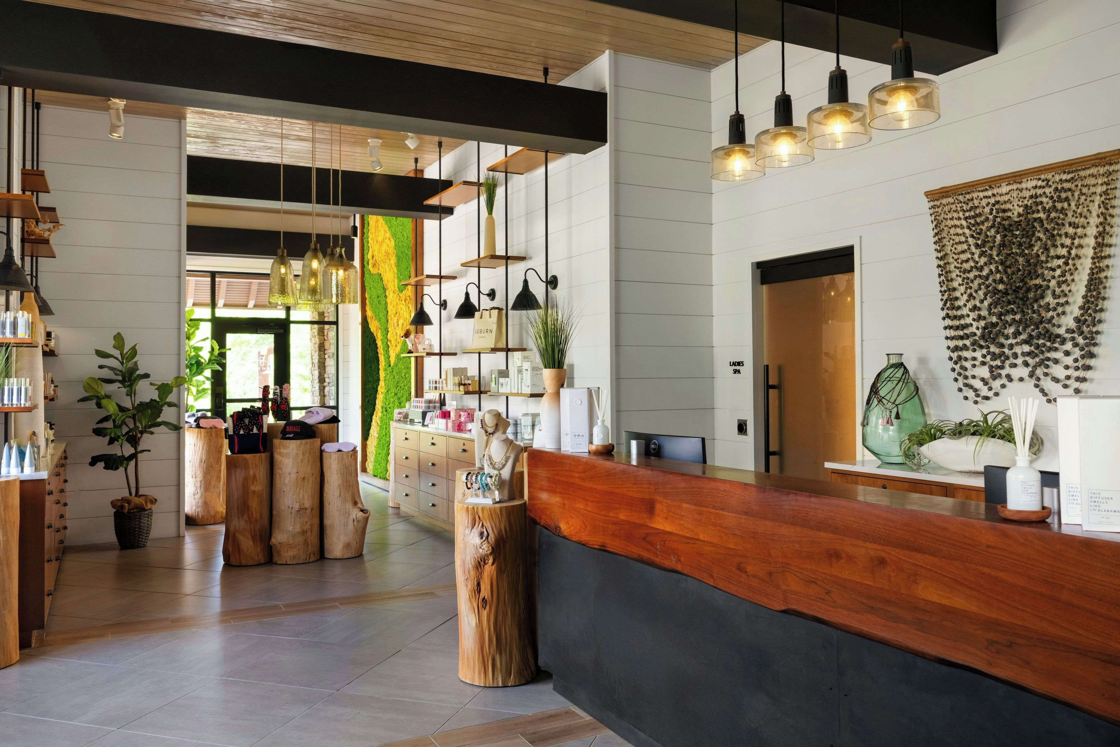 A modern interior with a wooden reception desk, pendant lighting, and a green wall accent.