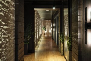 Un pasillo con paredes y suelo de madera que conduce a una habitación con pared de piedra y una planta.