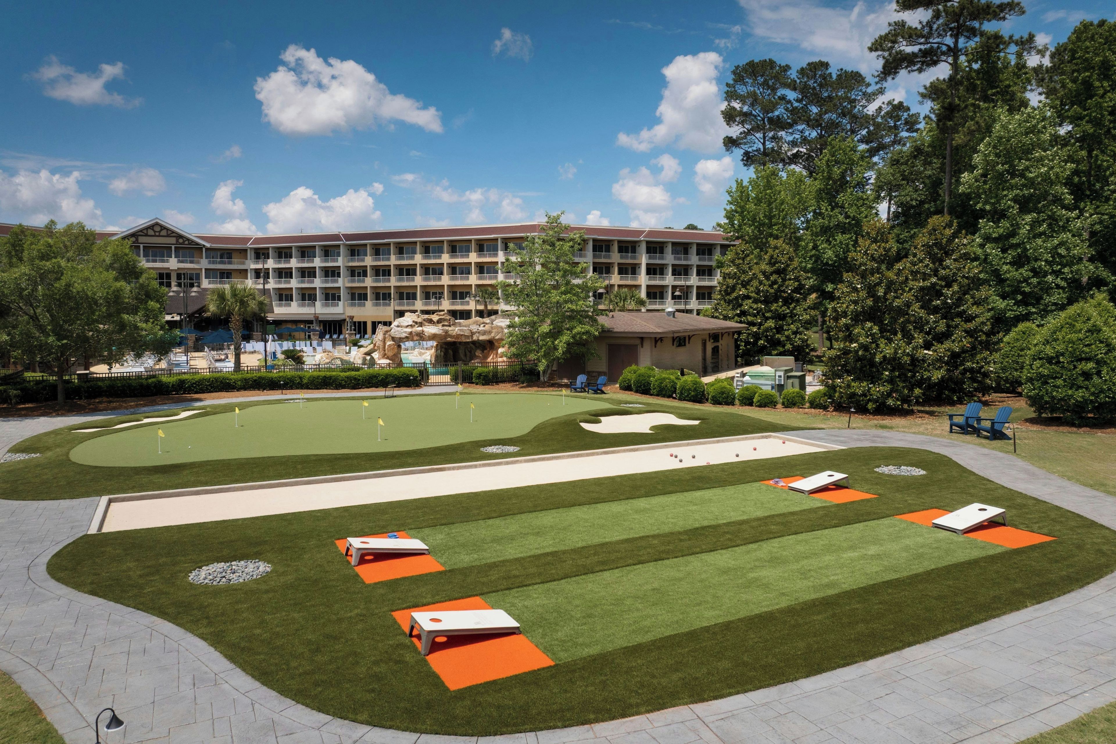 Un parcours de golf avec des bunkers, un green d’entraînement et un bâtiment doté de nombreux balcons en arrière-plan.