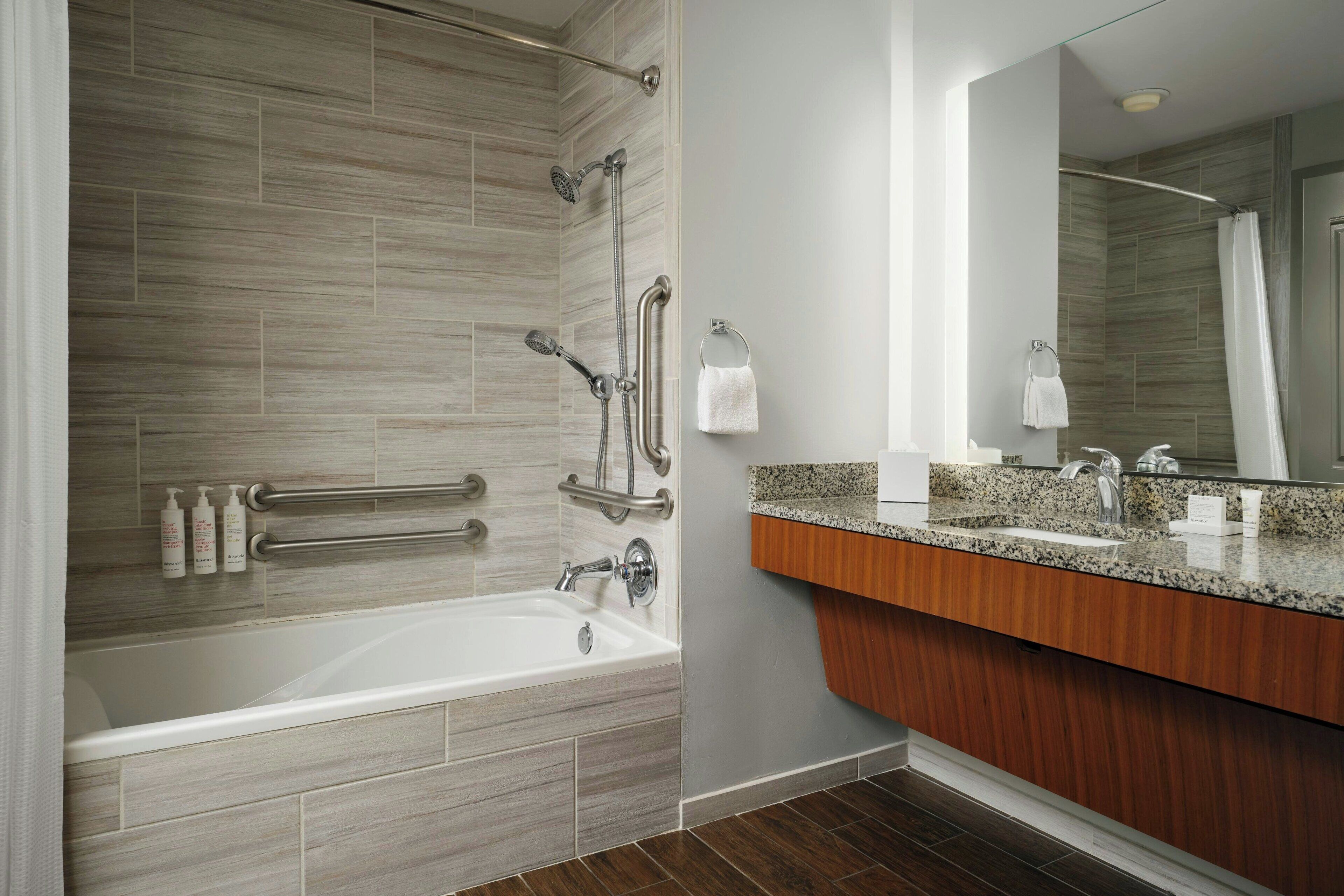 A modern bathroom with a bathtub, shower, and vanity.