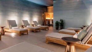 Ein Wellnessbereich mit mehreren Holzliegen, einer Holzkommode und einer Decke mit eingelassener Beleuchtung.