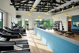 Un gimnasio con cintas de correr, máquinas de pesas y un mostrador azul.