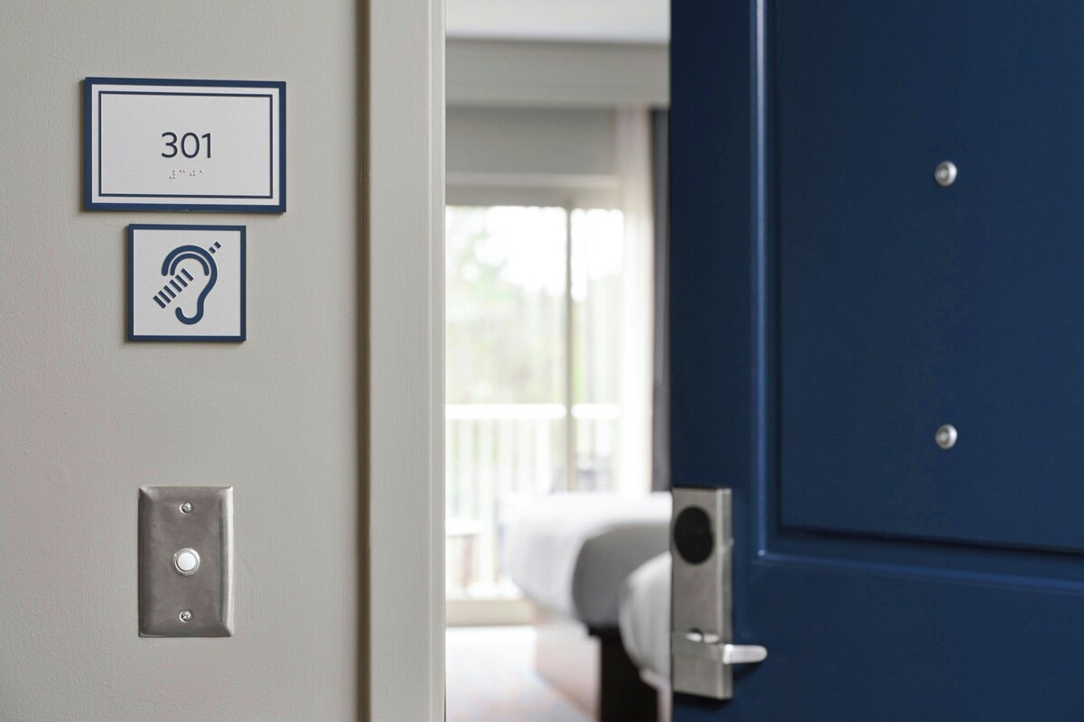 Una puerta con una placa numérica que indica '301' y un símbolo que representa un dispositivo de audio.