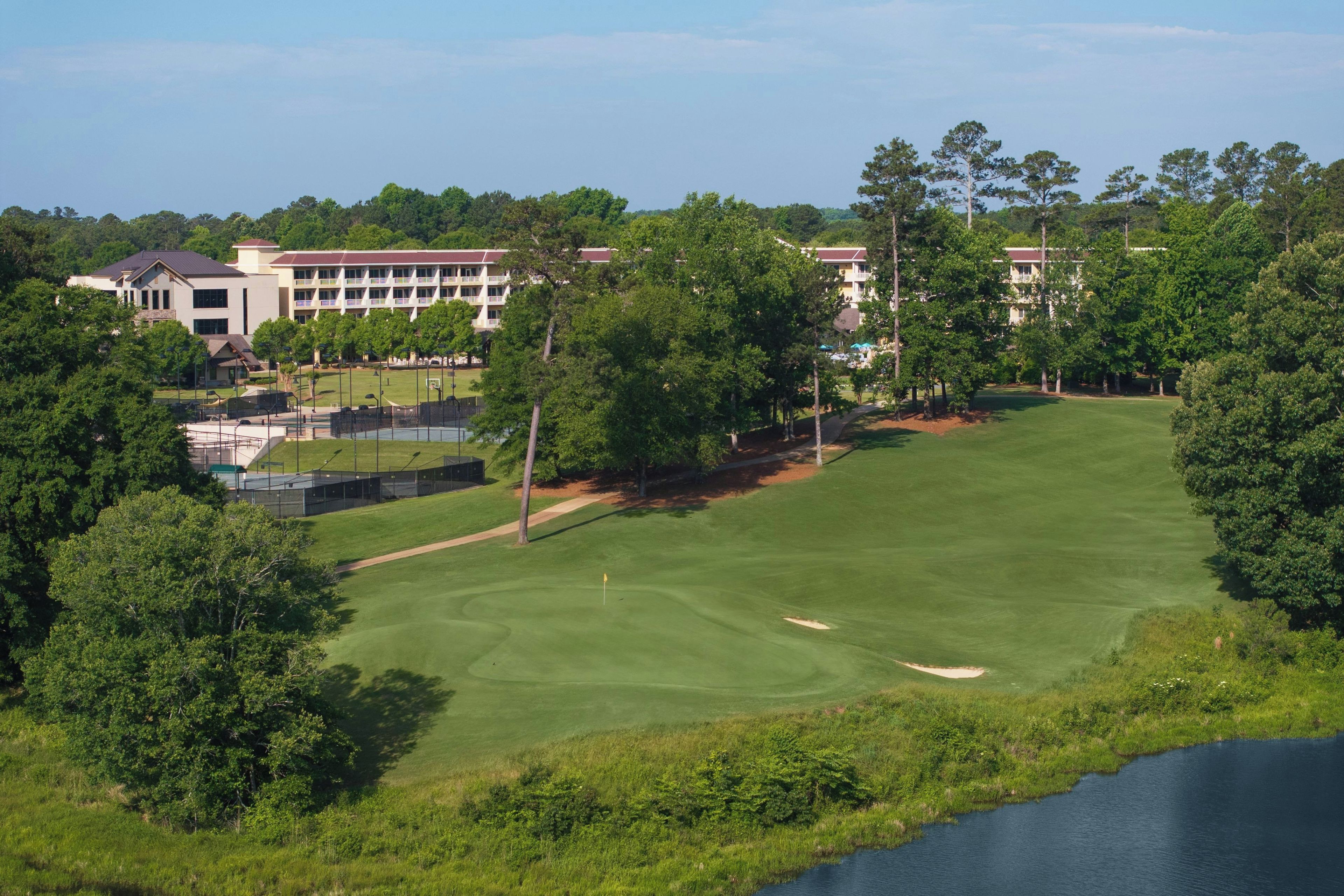 A golf course with a clubhouse and a building in the background.