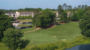 A golf course with a clubhouse and a building in the background.