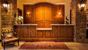 A reception area with a wooden reception desk, stone walls, a patterned rug, and a decorative chair.