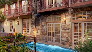 A stone building with a pool, balconies, and outdoor lighting.