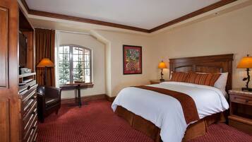 A hotel room with a large bed, a desk, a chair, a window, and a painting on the wall.