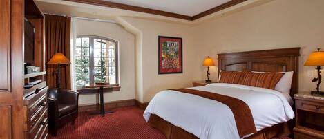 A hotel room with a large bed, a desk, a chair, a window, and a painting on the wall.