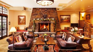 A cozy living room with leather sofas, a fireplace, and a staircase.