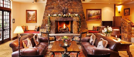 A cozy living room with leather sofas, a fireplace, and a staircase.