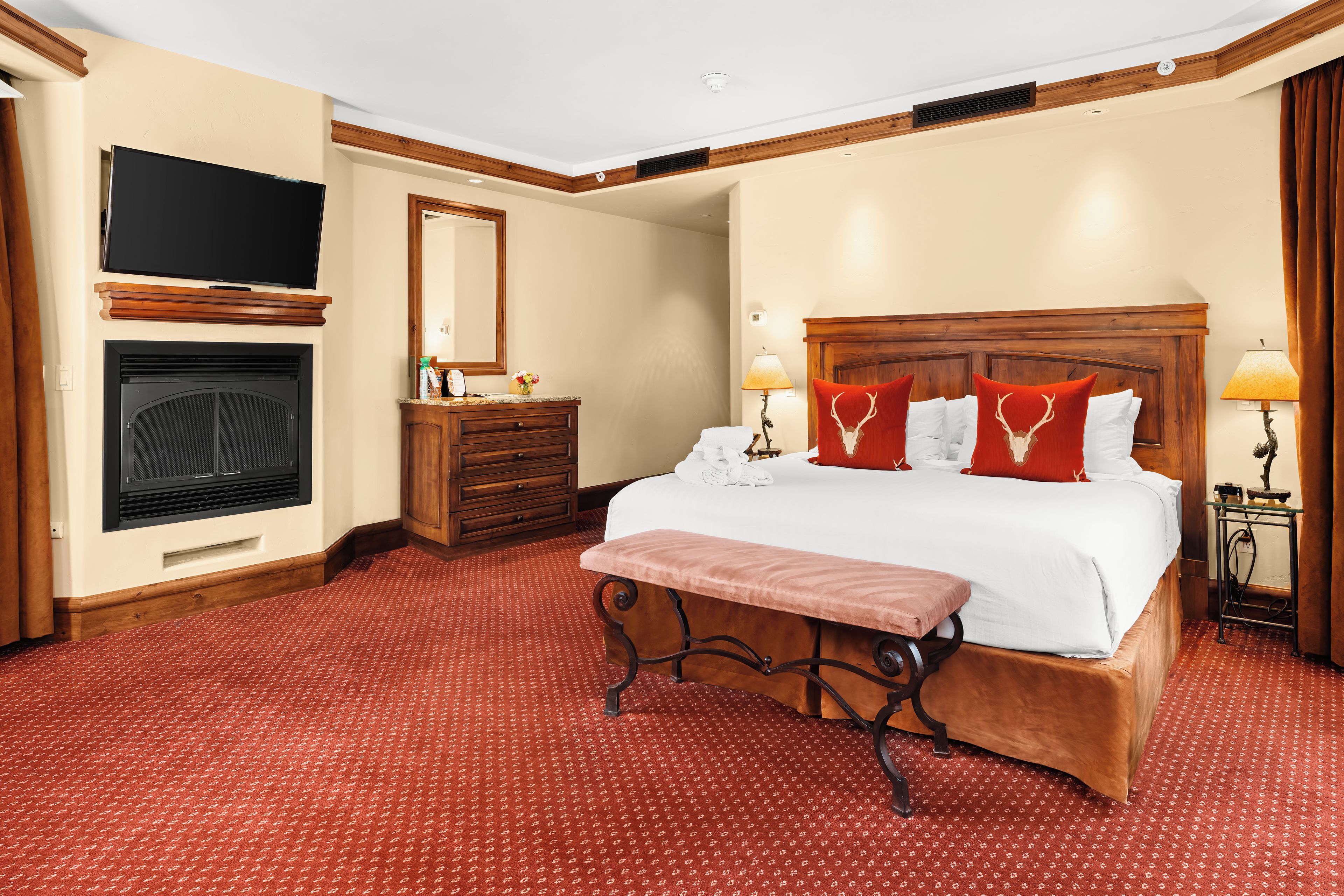 A hotel room with a large bed, a television, a fireplace, and a wooden headboard.