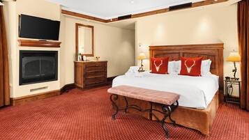 A hotel room with a large bed, a television, a fireplace, and a wooden headboard.