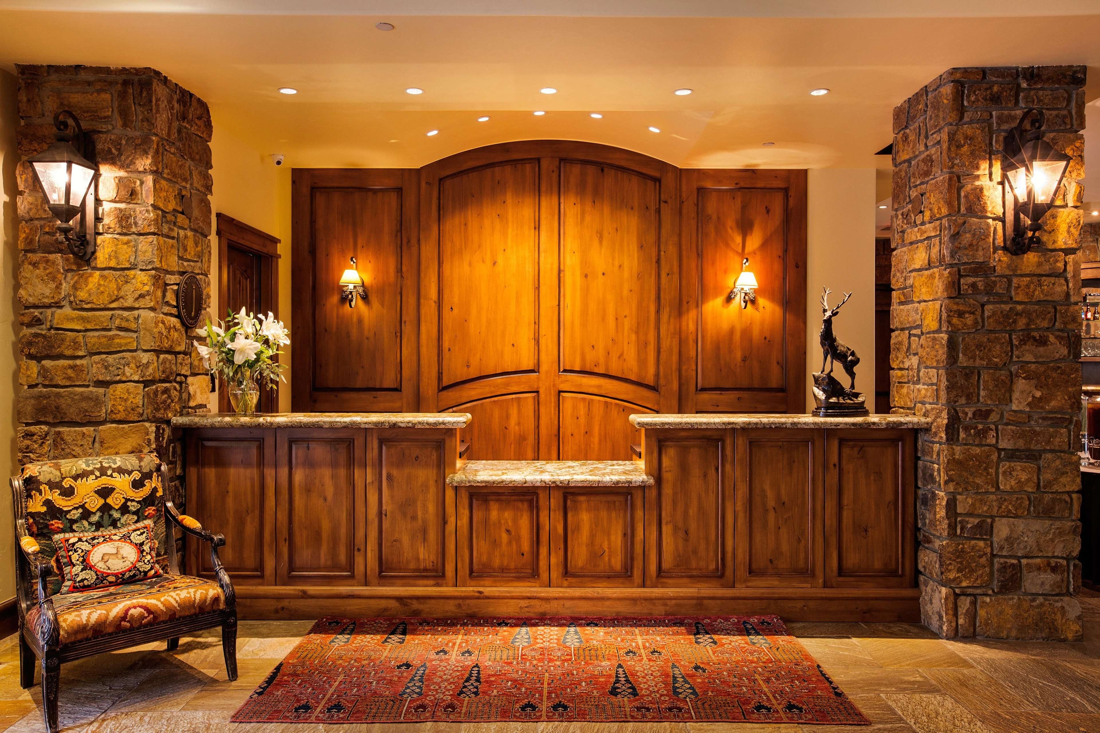 A reception area with a stone wall, wooden paneling, a bench, and a rug.