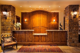 Un área de recepción con pared de piedra, paneles de madera, un banco y una alfombra.