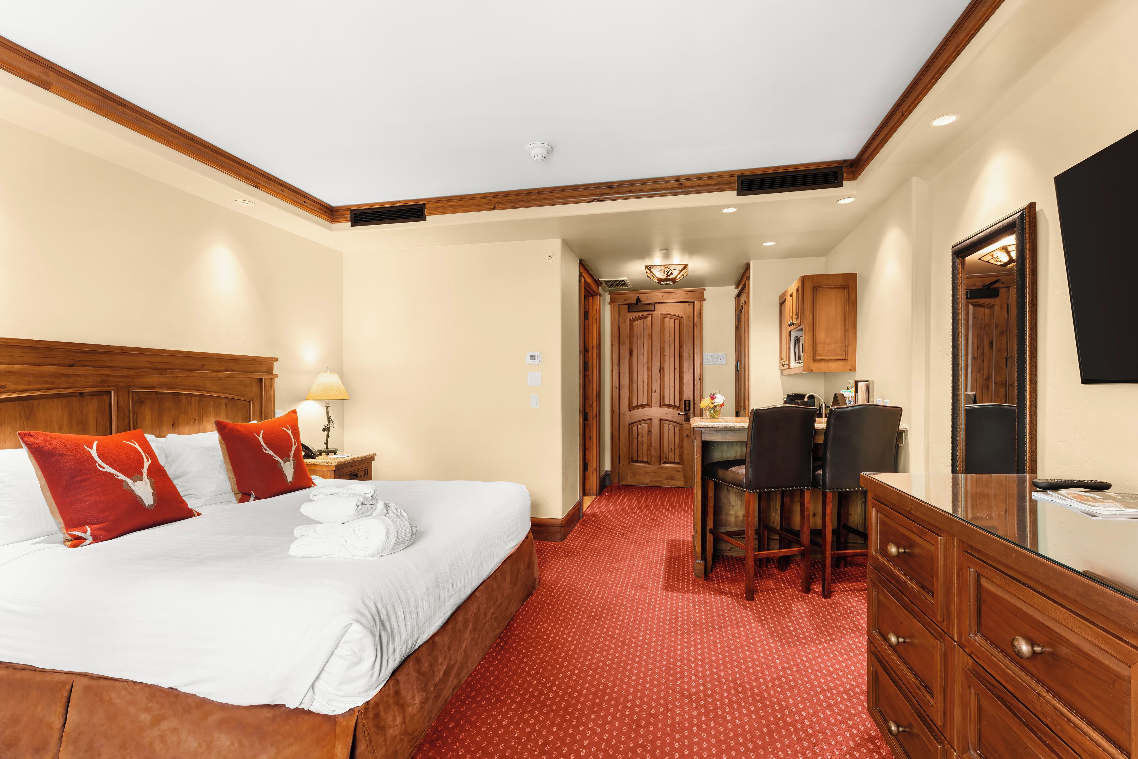 Une chambre d’hôtel équipée d’un lit, d’un bureau, d’un miroir et d’une kitchenette.