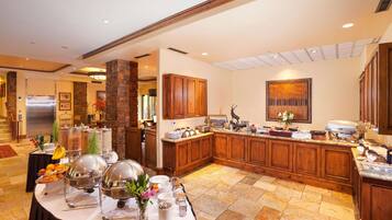 A spacious kitchen with wooden cabinets, a granite countertop, and a breakfast buffet setup.