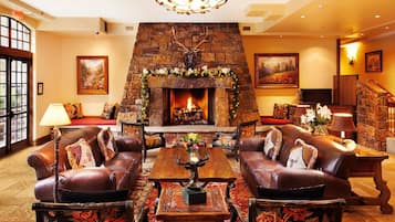 A cozy living room with leather sofas, a fireplace, and a stone wall.