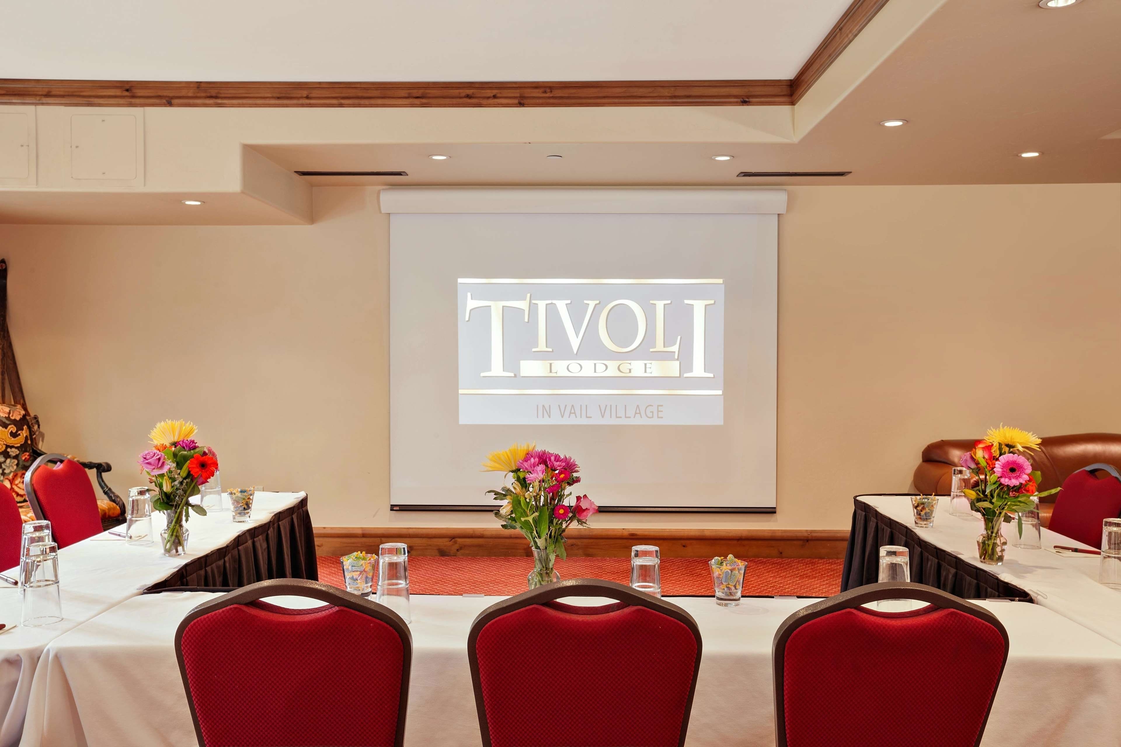 Ein Konferenzraum mit einer Projektionsleinwand, auf der 'TIVOLI LODGE IN VAIL VILLAGE' zu sehen ist.