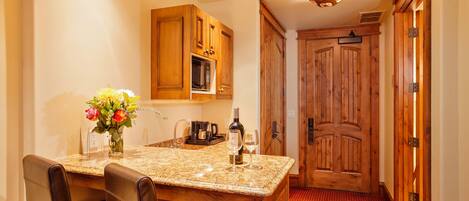 A kitchen with wooden cabinets, a granite countertop, and a dining area with leather chairs.