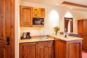 A kitchen with wooden cabinets, a built-in microwave, a sink, and a countertop with a coffee maker and a vase of flowers.