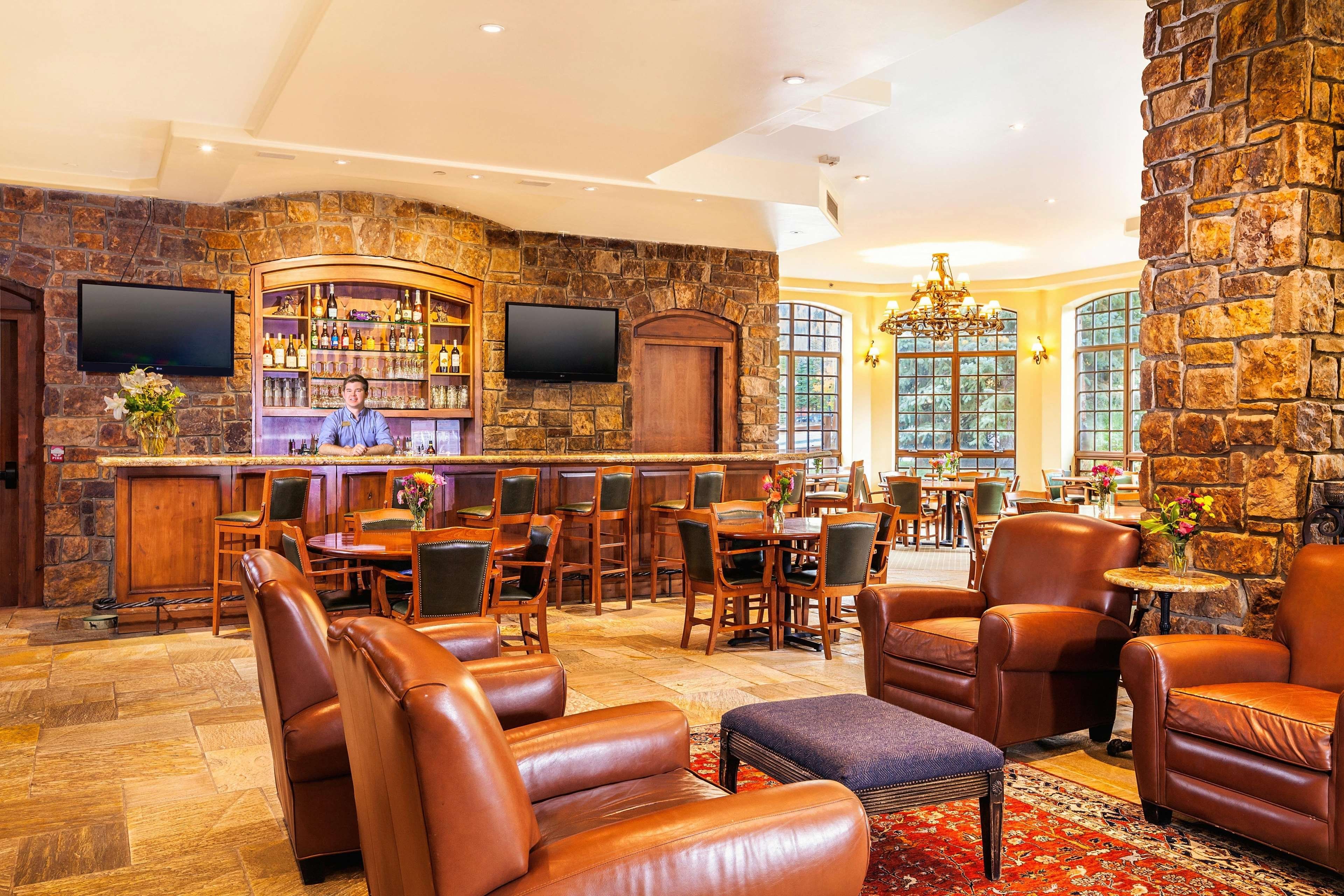 A bar area with a stone wall, wooden furniture, and a television.