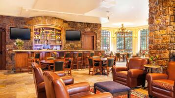 A bar area with a stone wall, wooden furniture, and a television.
