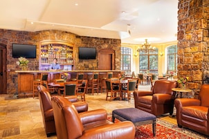 A bar area with a stone wall, wooden furniture, and a television.