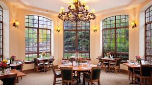 A dining area with round tables, chairs, and a chandelier.