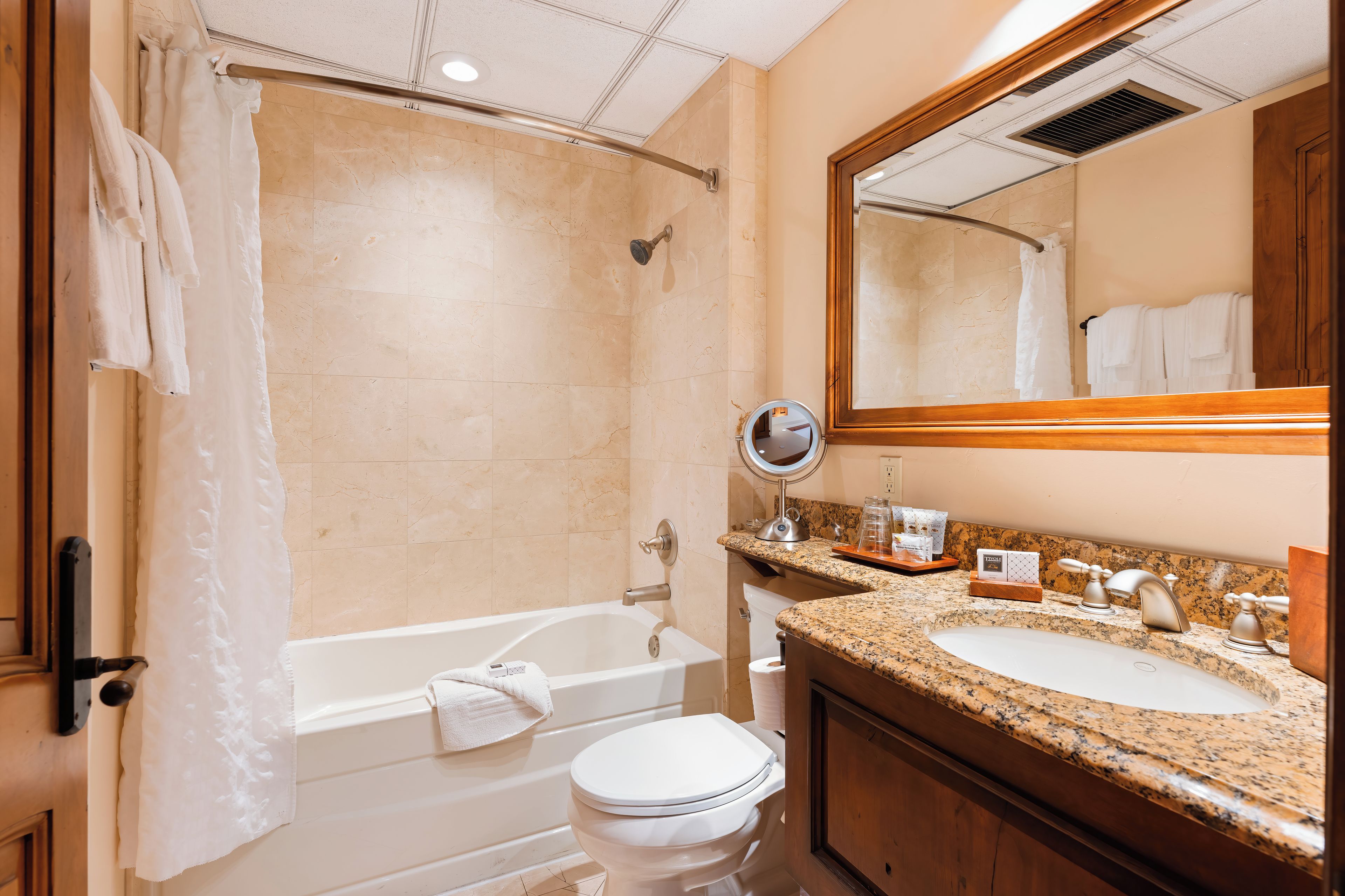 A bathroom with a bathtub, a toilet, a sink, and a mirror.
