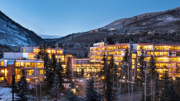 Moderni hotellikompleksi, jossa on useita rakennuksia, ja se sijaitsee lumipeitteisten puiden ja vuorten ympäröimänä.