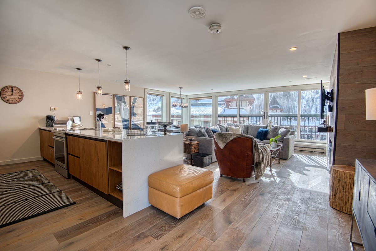 A modern kitchen with wooden cabinets, a large island, and pendant lighting.