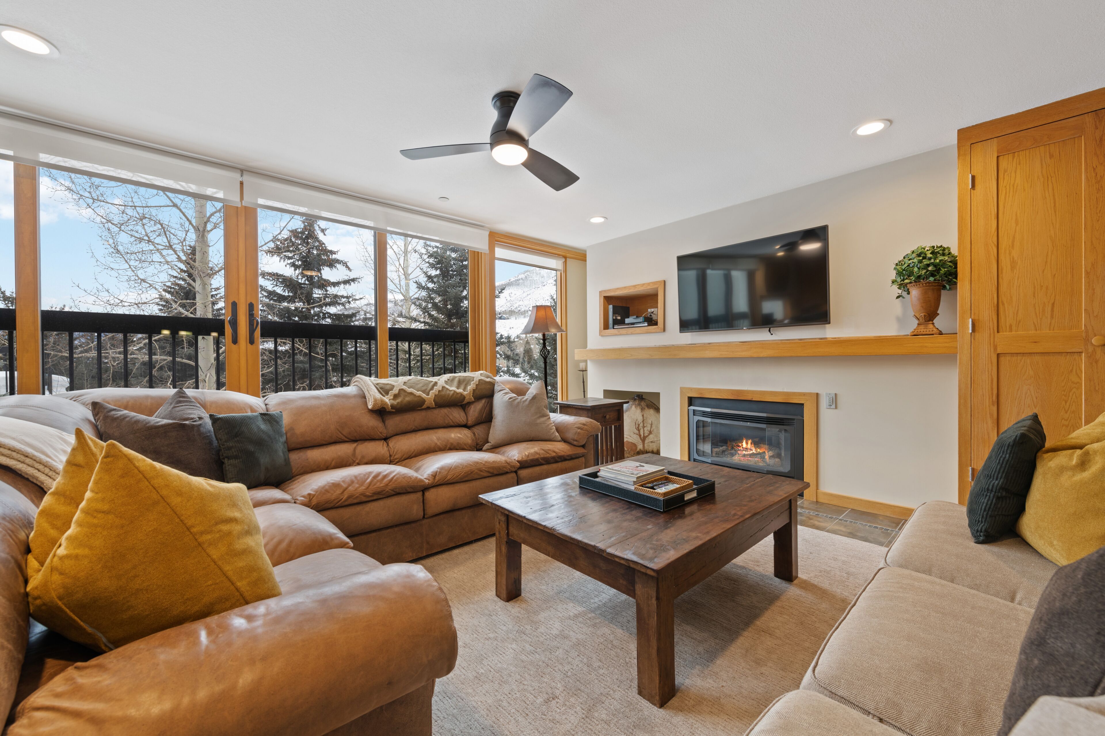 A spacious living room with a large leather sofa, a wooden coffee table, and a fireplace.