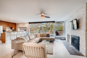 Una sala de estar moderna con un sofá seccional, una mesa de centro de vidrio y una chimenea.